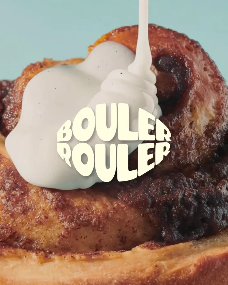 Du glaçage blanc coule sur un cinnamon roll, le logo au centre