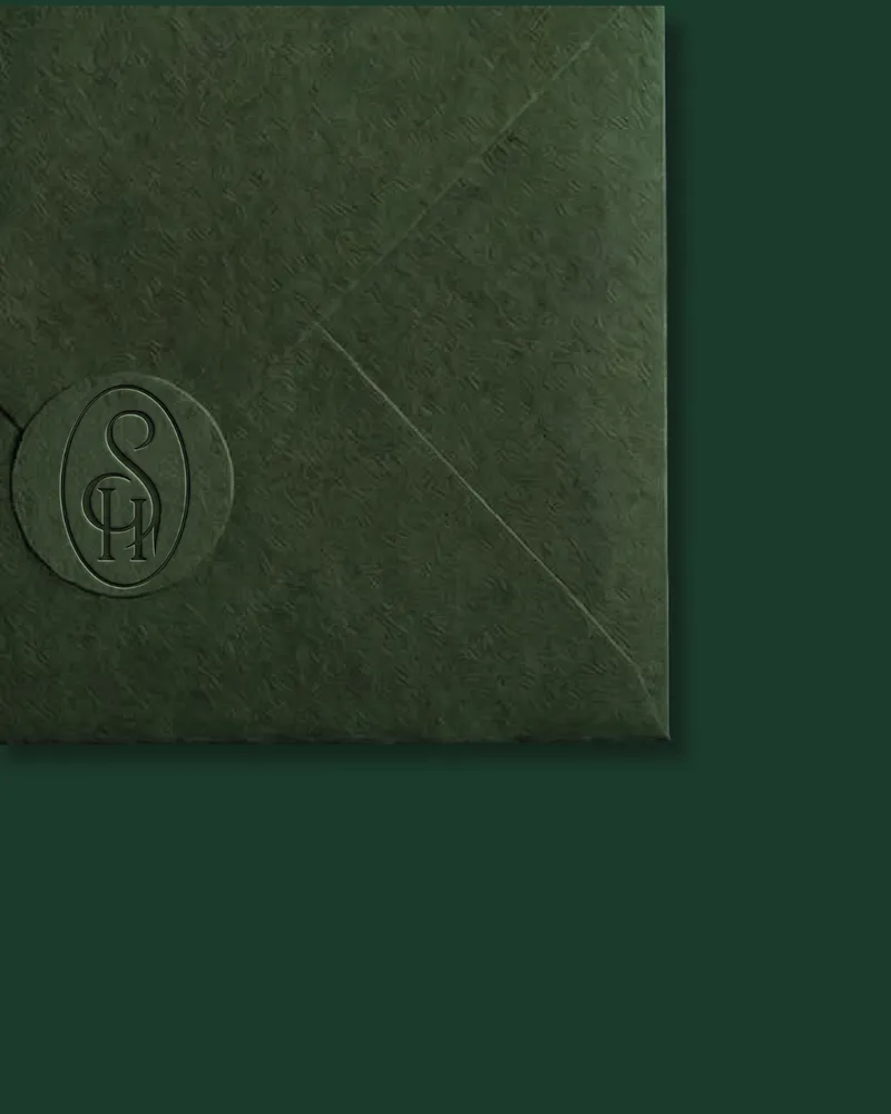 Enveloppe vert foncé fermée par un sceau gaufré portant le monogramme