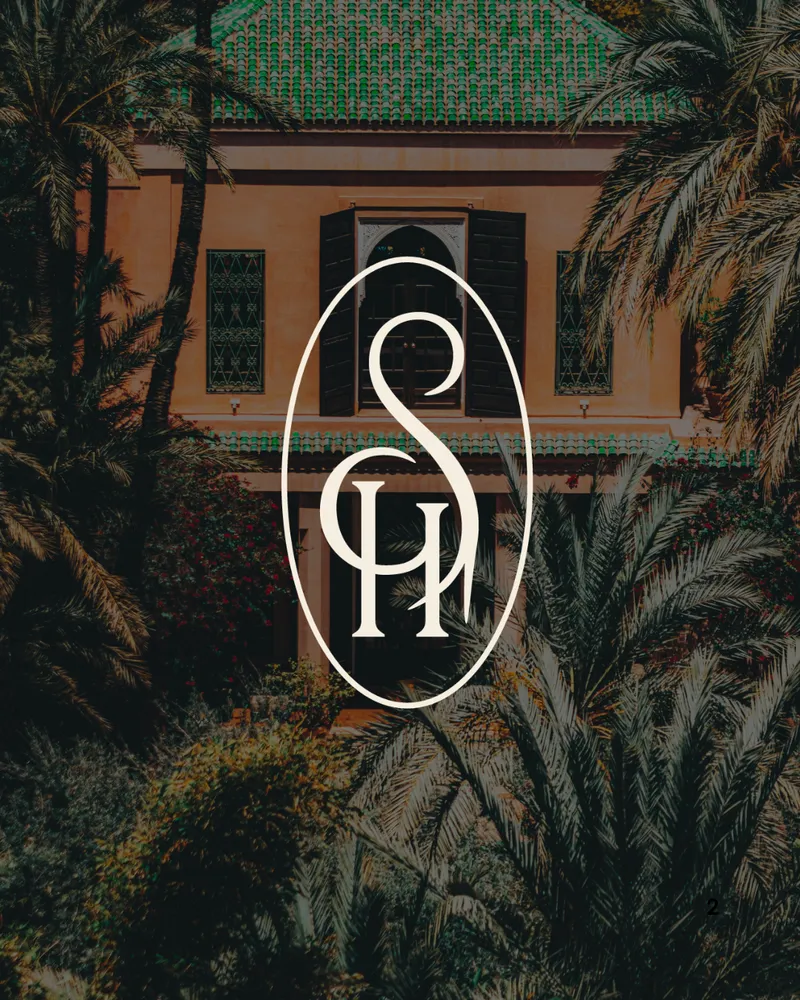 Le monogramme S et H de So Habana, crème dans un ovale, sur la façade d’un riad entourée de palmiers